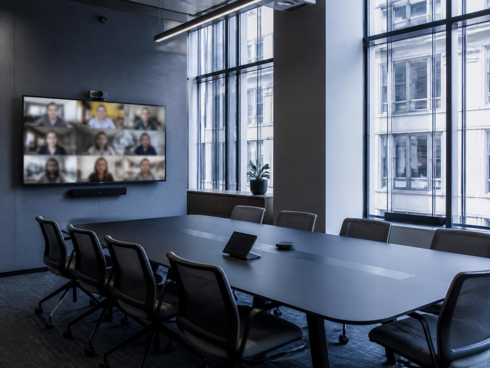 An empty hybrid conference room with remote participants on a wall display